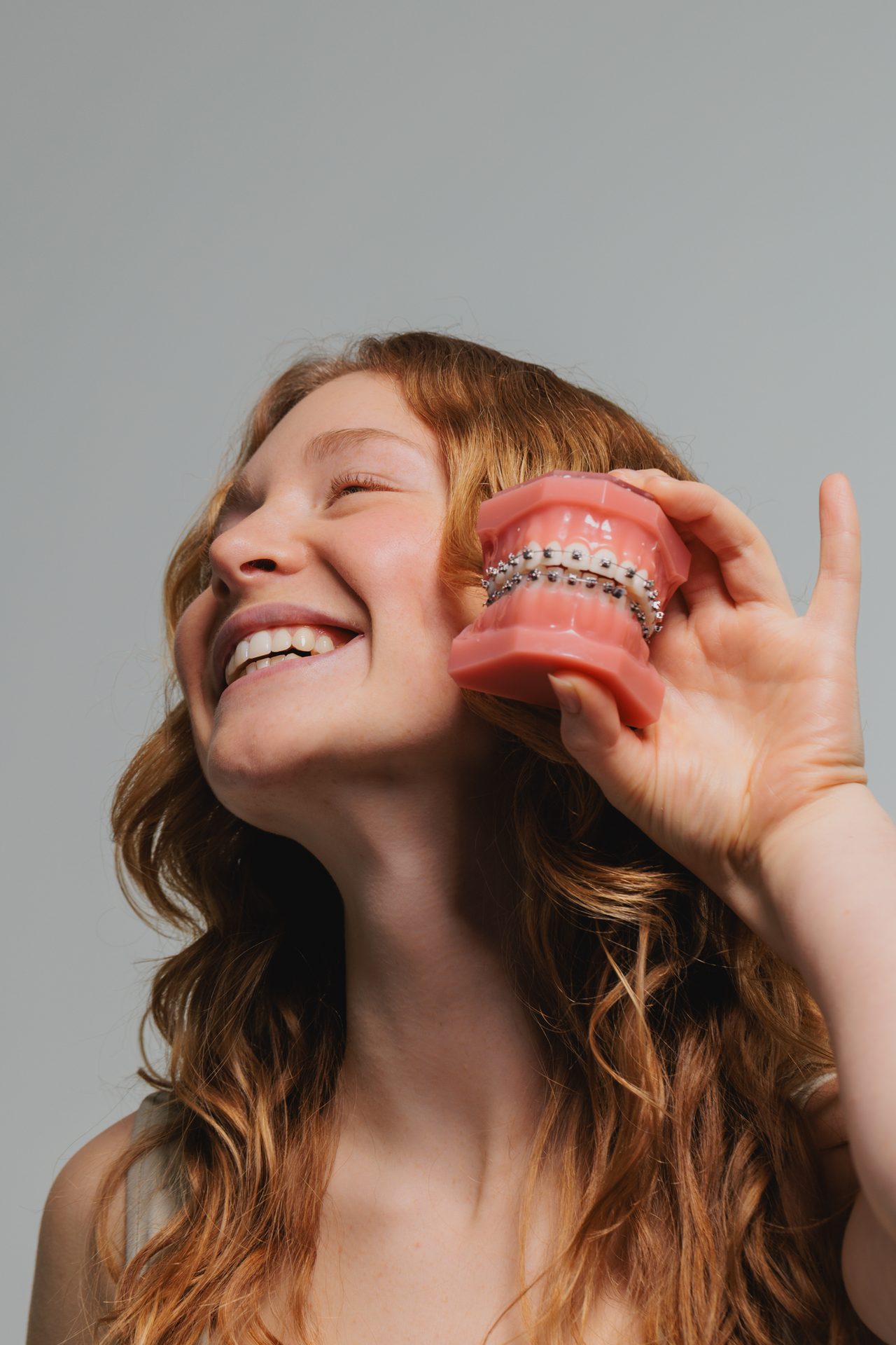 Lachende junge Patientin mit Kiefermodell und Brackets in der Kieferorthopädie Univ.-Prof. DDr. Jonke
